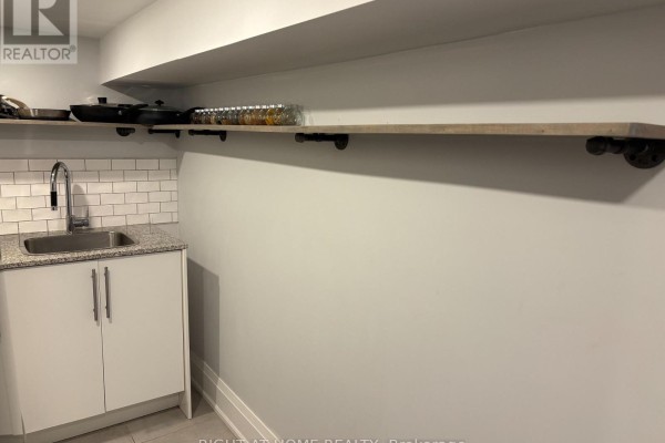Close-up of a stainless steel sink and white cabinets against a subway tile backsplash. - Lower - 39 Amherst Avenue, Toronto