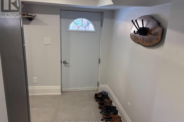 Hallway with a white door, round window, and a tree-slice coat rack mounted on the wall. - Lower - 39 Amherst Avenue, Toronto