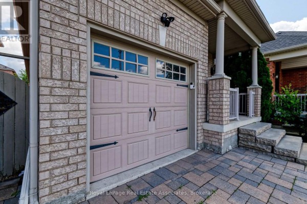 Close-up of a beige garage door with decorative windows and a concrete pathway. - Lower - 41 Greenview Circle, Vaughan