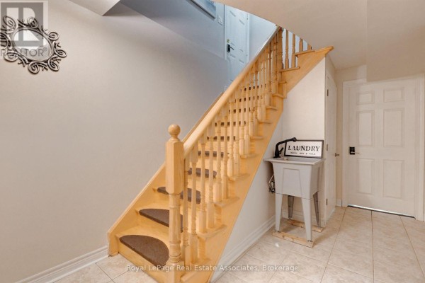 Wooden staircase with light-colored walls, a laundry sink, and tiled flooring. - Lower - 41 Greenview Circle, Vaughan