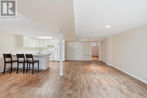 Open concept basement living area and kitchen with wood laminate flooring and white cabinets. - Lower - 531 Rodd Avenue, Pickering