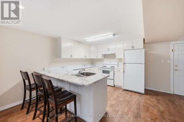 U-shaped white kitchen with marble countertop, white appliances, and wood laminate flooring. - Lower - 531 Rodd Avenue, Pickering