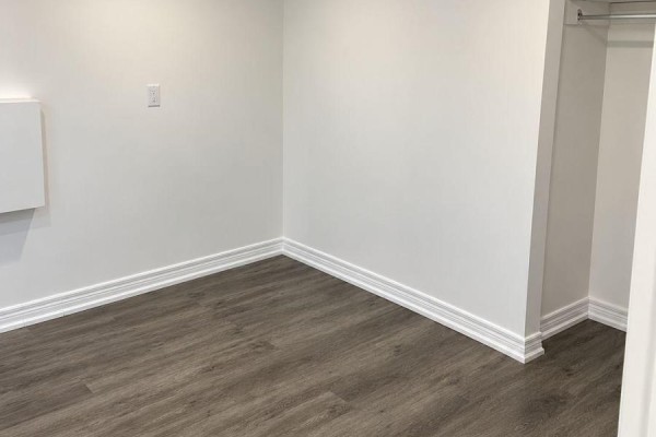 Corner of a room with white walls, white baseboards, grey wood-look flooring, and a closet. - Lower - 558 First Avenue, Welland