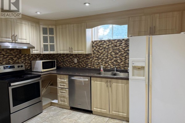 Close-up of basement kitchen with stainless steel appliances, mosaic backsplash, and wood cabinets. - Lower - 5689 Sidmouth Street, Mississauga
