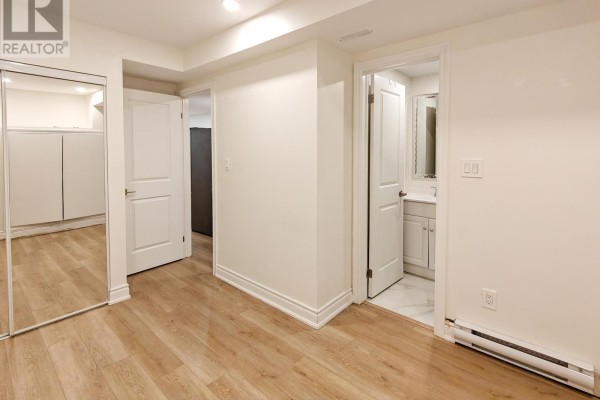 Interior hallway connecting rooms, including a bathroom with white vanity and mirrored closet. - Lower - 598 Crawford Street, Toronto