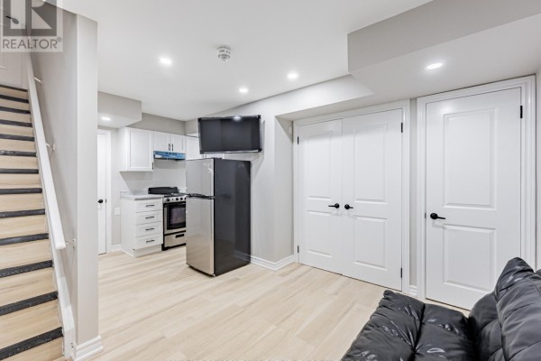 View of a basement living area with white double doors and a black sofa. - Lower - 6 Harper Hill Drive, Ajax