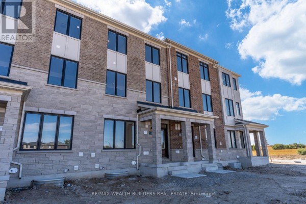 Side exterior view of the townhouse complex under a blue sky. - Lower - 6 Thornbird Crescent, Brampton