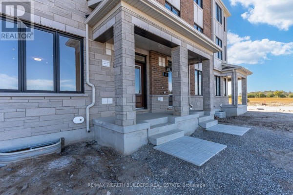 Close-up of townhouse entrances with concrete steps and stone pillars. - Lower - 6 Thornbird Crescent, Brampton
