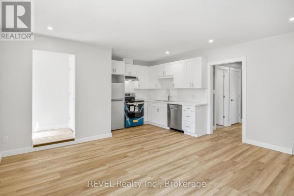 Open concept living room and kitchen area with white cabinets and light wood floors. - Lower - 6166 Wildrose Crescent, Niagara Falls