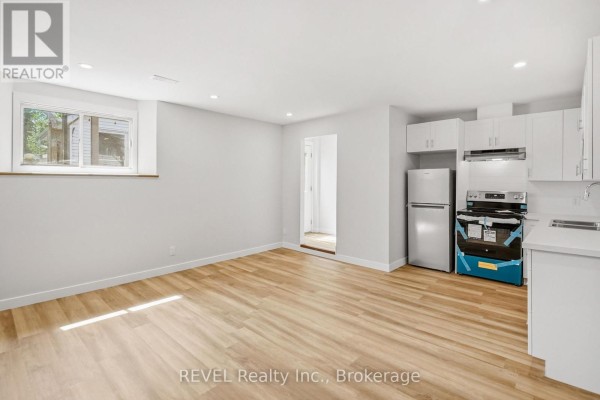 Kitchenette area with white cabinets, stainless steel appliances and light wood floors. - Lower - 6166 Wildrose Crescent, Niagara Falls