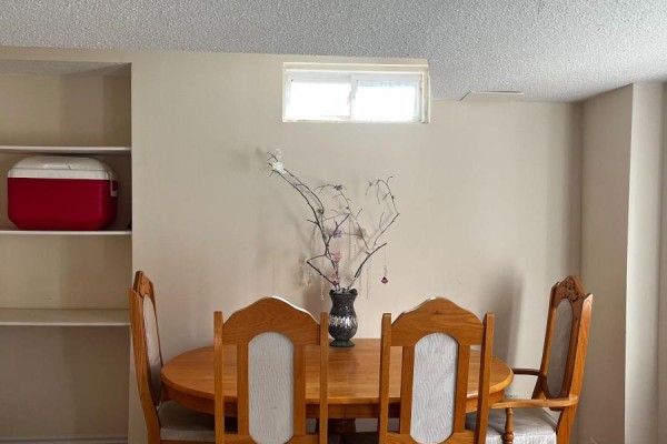 Dining area with a wooden table, chairs, and shelves against a beige wall. - Lower - 62 Grover Hill Avenue, Richmond Hill