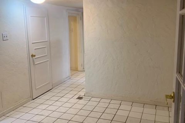 Hallway with white checkered tile floor, textured walls, and white paneled doors. - Lower - 730 Logan Avenue, Toronto