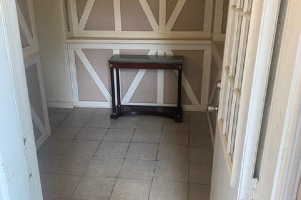 Entryway with checkered tile floor, decorative wall paneling, and a console table. - Lower - 730 Logan Avenue, Toronto