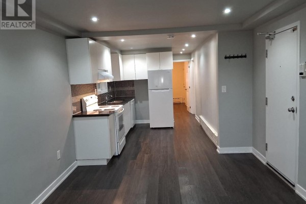 View of a small apartment kitchen and living area with dark wood floors. - Lower - 78 Cavell Avenue, Toronto