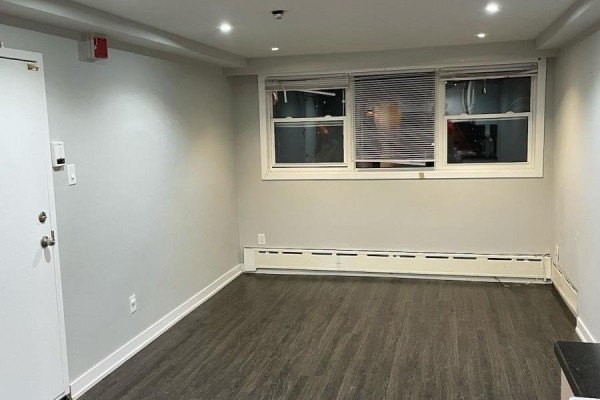 Living area with dark wood floors, pale grey walls, and two windows. - Lower - 78 Cavell Avenue, Toronto