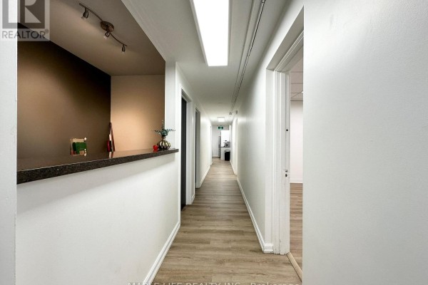 Long hallway with a bar counter, bright lighting, and white walls. - Lower - 901 Yonge Street, Toronto