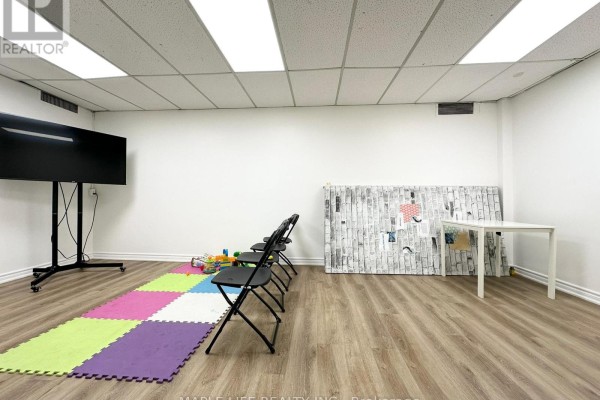 Interior room with chairs, colorful mats, and a television screen on a stand. - Lower - 901 Yonge Street, Toronto