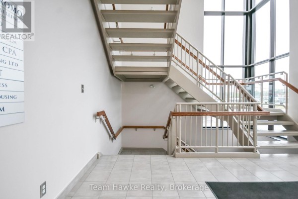Interior staircase with metal railings and tiled flooring in a commercial building lobby. - Lower - 9170 County 93 Road, Midland