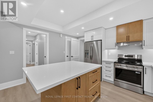 Kitchen with white quartz island, light wood base cabinets, and white upper cabinets with stainless steel appliances. - Lower - 933 7th Line, Innisfil