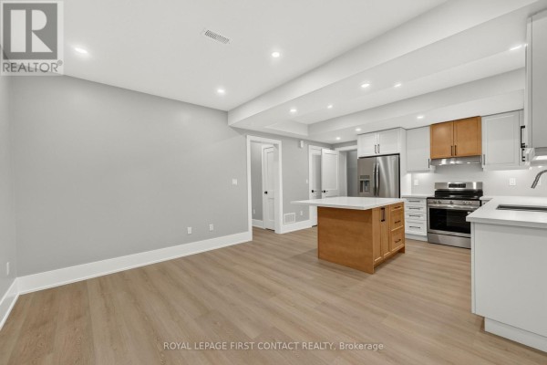 Open concept living area and kitchen with light wood flooring, island, and white and wood cabinetry. - Lower - 933 7th Line, Innisfil