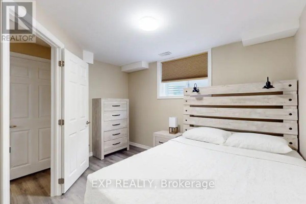 Bedroom with a king-sized bed, light wood headboard, a dresser, and an adjacent closet door. - Lower - 967 Wright Drive, Midland