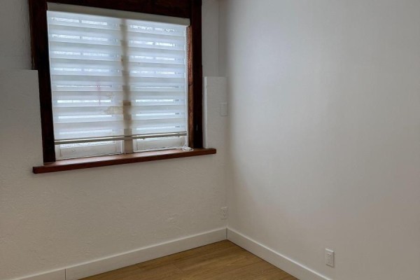 Bedroom corner with white walls, wood-look flooring, and a window with horizontal blinds. - Lower 2 - 233 Ellerslie Avenue, Toronto