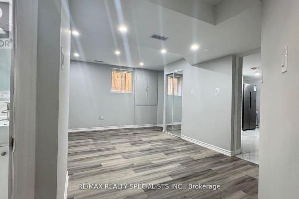 A spacious room with grey walls, light wood laminate flooring, and mirrored closet doors. - Lower 2-b - 3 Lennon Trail, Brampton