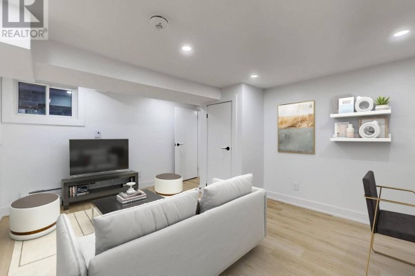 Living area with sofa, television, and artwork on the wall, facing white doors and a small window. - Lower F - 250 Major Street, Toronto