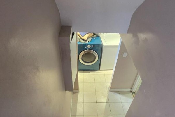 View from above looking down at a blue washing machine and white dryer in a tiled room. - Lower Level - 15 North Bonnington Avenue, Toronto