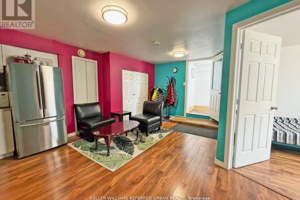 Living area with dark leather chairs, coffee table, rug, and stainless steel refrigerator. - Lower Level - 6 Elmhurst Drive, Toronto
