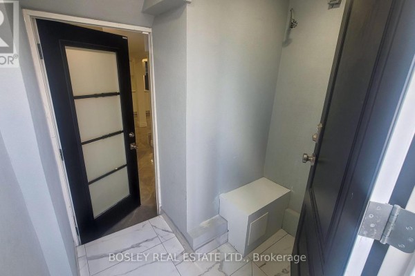 Interior entryway with light grey walls, black door, and white bench. - Lower Level - 623 Dupont Street, Toronto