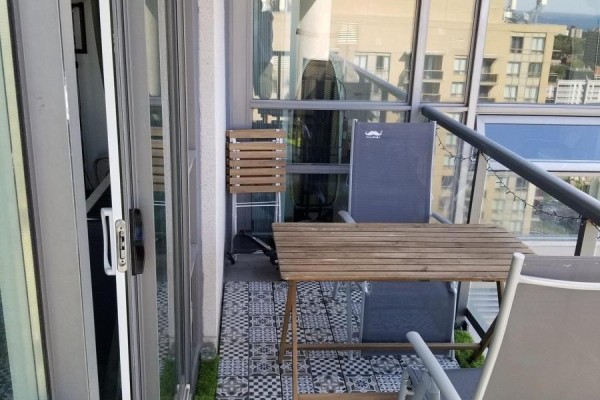Balcony with foldable chairs and table on patterned tile flooring, overlooking city buildings. - Lp-09 - 68 Abell Street, Toronto
