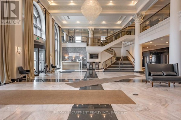 Spacious lobby with marble floors, reception desk, grand staircase, and seating area. - Lph01 - 112 King Street E, Hamilton