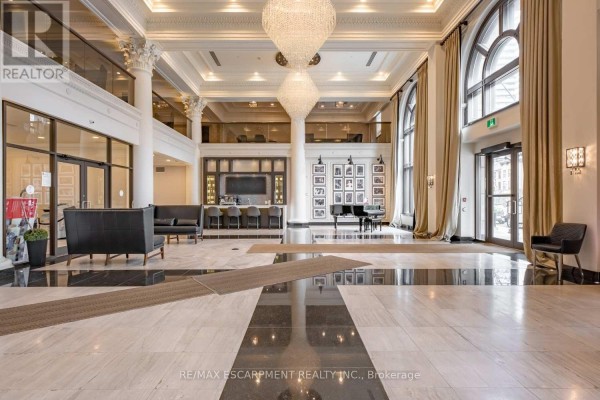 Grand lobby with high ceilings, chandeliers, piano, bar area, and large arched windows. - Lph01 - 112 King Street E, Hamilton