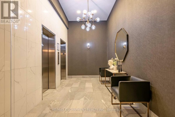 Elevator lobby with modern fixtures, textured walls, decorative mirror, and bench seating. - Lph01 - 112 King Street E, Hamilton