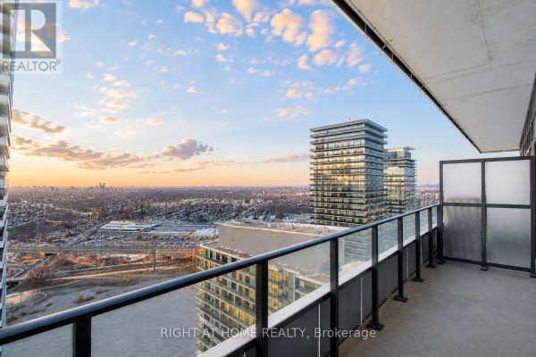 Living room and kitchen area with light wood floors, neutral furniture, and white cabinetry. - Lph02b - 20 Shore Breeze Drive, Toronto