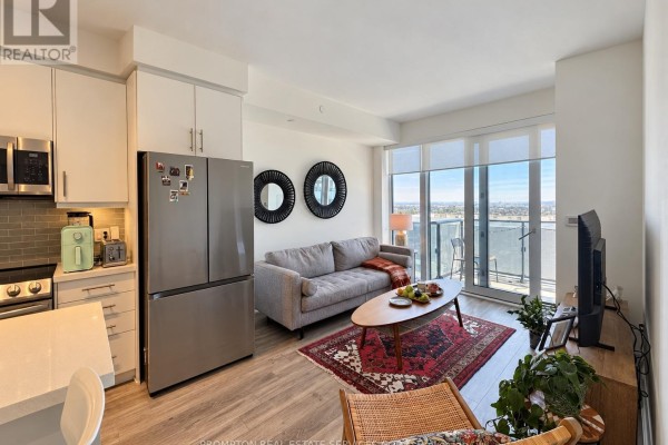 Open concept living area with kitchen, sofa, and balcony access. - Lph06 - 95 Oneida Crescent, Richmond Hill