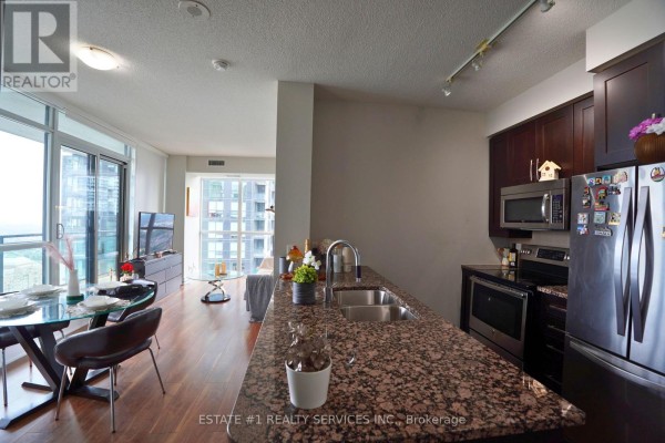 Open concept living and kitchen area with dark wood cabinets and granite countertops. - Lph2 - 4065 Brickstone Mews, Mississauga