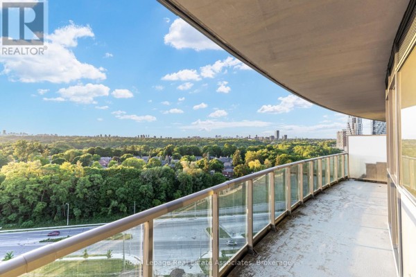 Balcony with glass railings overlooking a treed landscape and distant city skyline. - Lph21 - 35 Brian Peck Crescent, Toronto