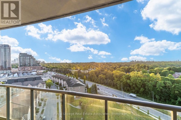 View from the balcony showing townhouses, a street, trees, and city buildings. - Lph21 - 35 Brian Peck Crescent, Toronto