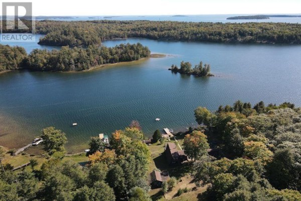 View of the property from the dock, showing the house, yard, and waterfront amenities. - Lt 10 Pl M90 Long Twp, Sugar Island, Lake Lauzon, Algoma Mills