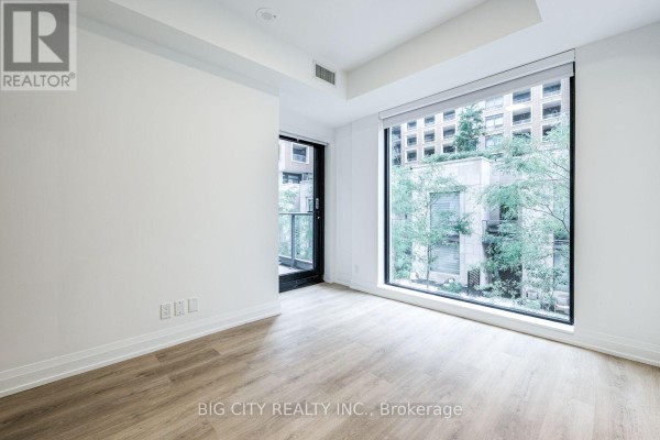 Empty bedroom with a large window and a balcony door. - M05 - 36 Brentcliffe Road, Toronto