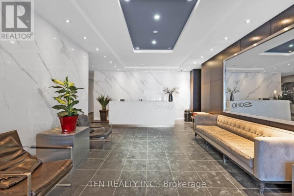 Apartment building lobby with a white reception desk, tan sofa, tiled floor, and marble walls. - M22 - 350 Wellington Street W, Toronto