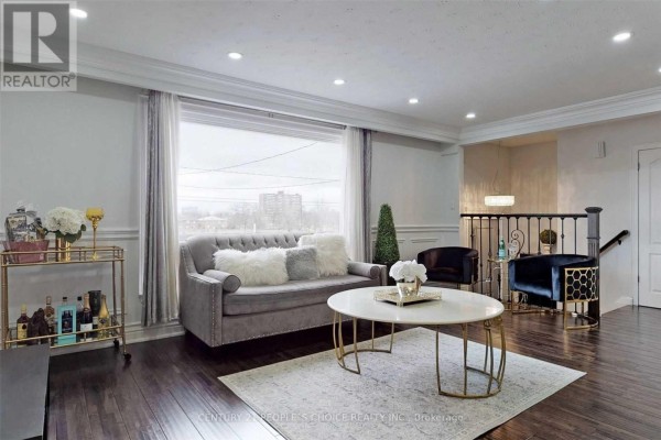 Living room with a grey sofa, coffee table, and large picture window. - Main - 107 Spenvalley Drive, Toronto