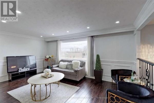Living room with sofa, coffee table, television, and decorative wall panels. - Main - 107 Spenvalley Drive, Toronto