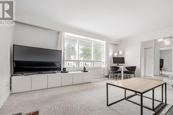 Living room with a television, white media console, and a desk with two chairs by the window. - Main - 11 Greenbriar Road, Toronto