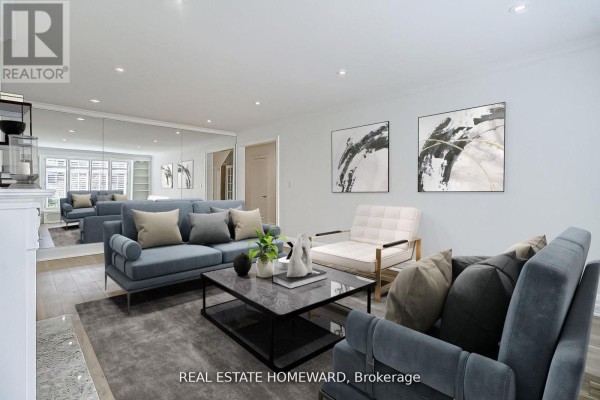 Living room with blue sofas, a white armchair, and a mirrored wall reflecting the space. - Main - 12 Highbourne Road, Toronto