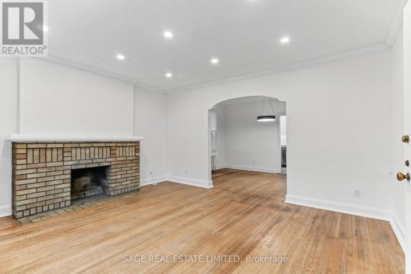 Living room with hardwood floors and an arched doorway leading to a dining area. - Main - 121 Braemar Avenue, Toronto