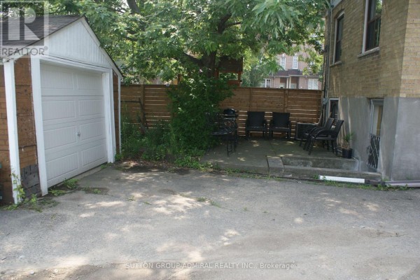 Backyard patio with chairs, a barbecue, a wooden fence, and a detached garage. - Main - 131 Times Road, Toronto