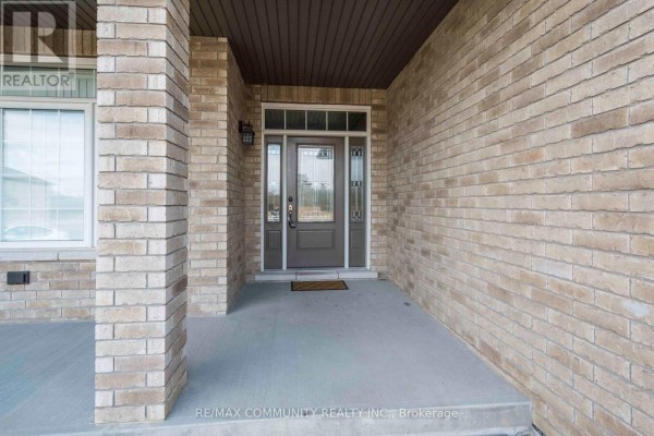 Close-up of the covered front entryway with a glass-paneled front door and brick pillars. - Main - 19 Bevan Drive, Belleville